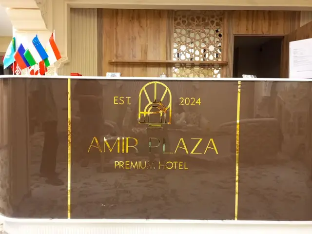 AMIR PLAZA PREMIUM HOTEL: золотой логотип и зеркальные буквы на глянцевой панели ресепшена отеля