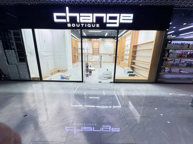 change boutique: световая вывеска бутика в торговом центре с проекцией логотипа на пол
