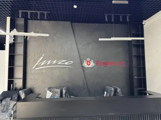 imzo · Engelberg: интерьер шоурума: логотипы imzo и Engelberg на стенах, подвесные световые короба-навигация над экспозицией