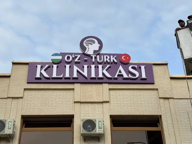 O‘Z-TURK KLINIKASI: объёмные буквы с логотипом на фиолетовой подложке над фасадом клиники