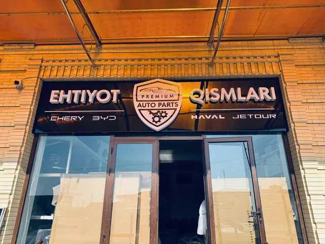 EHTIYOT QISMLARI · PREMIUM AUTO PARTS: вывеска с объёмными буквами и логотипом над входом, логотип с контражурной подсветкой и стена с логотипами автобрендов в интерьере