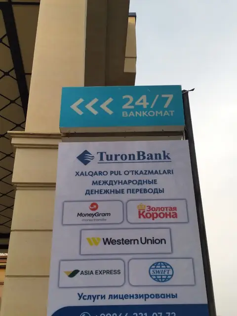 TuronBank 24/7 Bankomat: уличный пилон с логотипами систем денежных переводов и табличка режима работы на фасаде