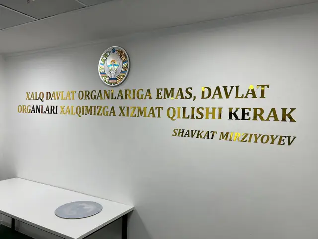 Xalq davlat organlariga emas…: цитата из золотых букв с гербом в интерьере