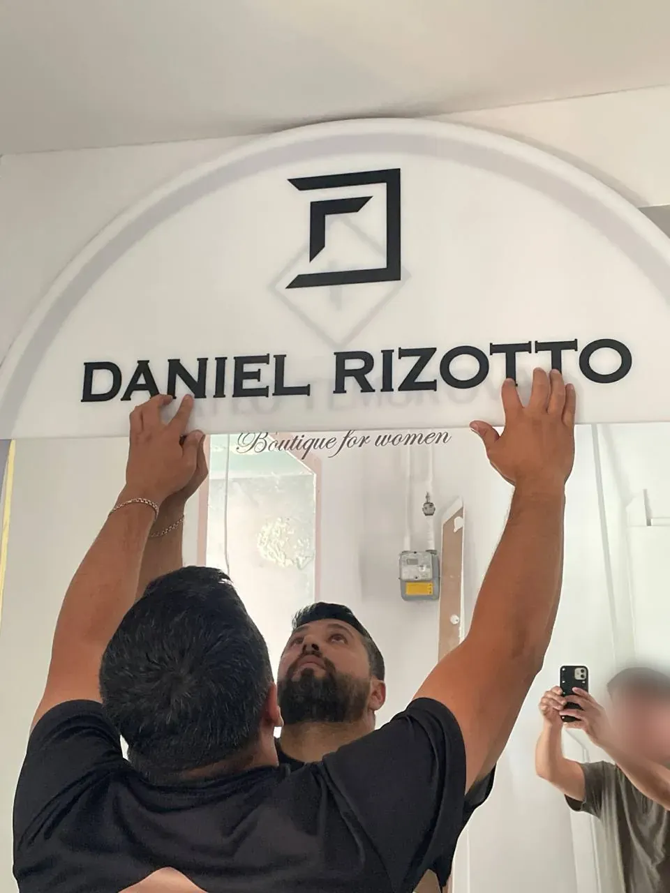 Монтажник нашей бригады крепит вывеску Daniel Rizotto над входом