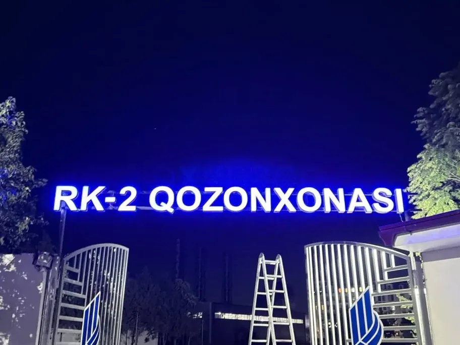 Крышные световые буквы RK-2 Qozonxonasi ночью, внизу монтажники с лестницей